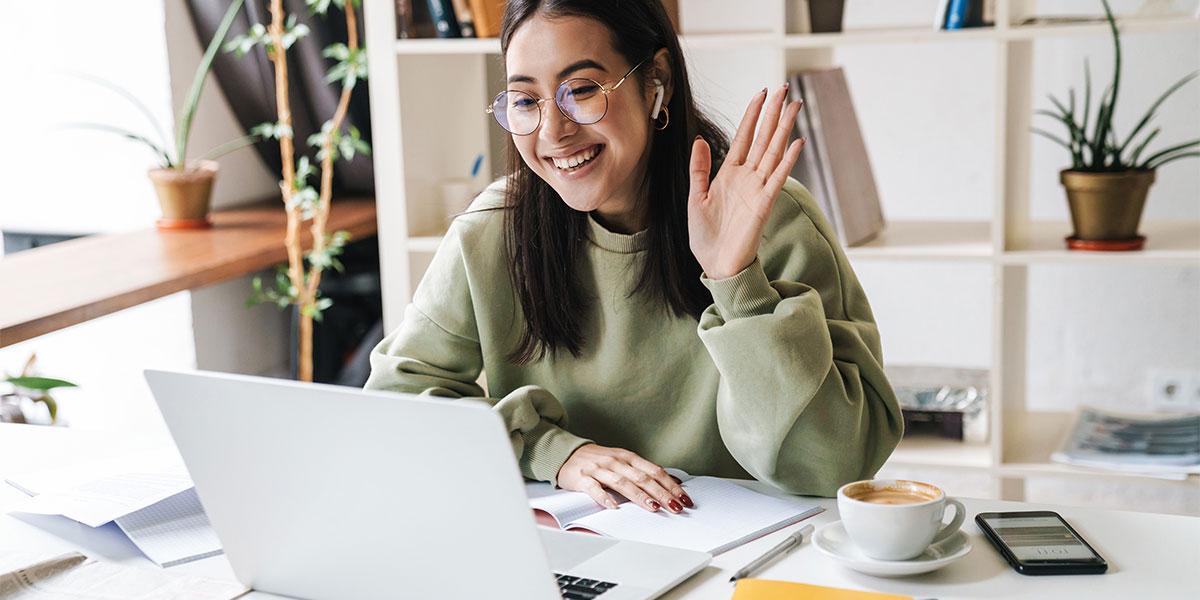 Student waves at her computer.